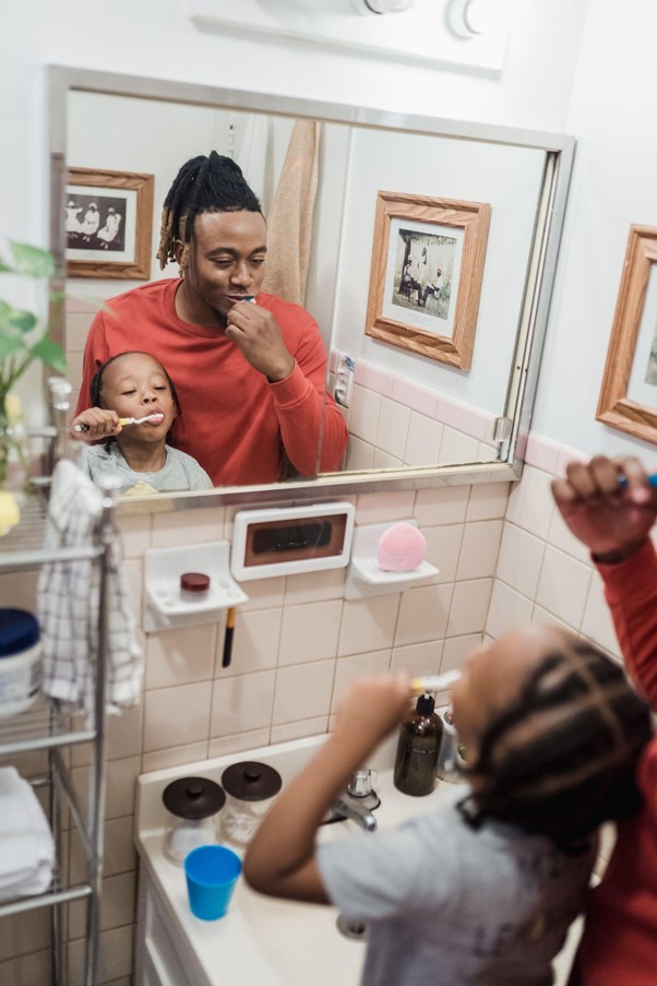 Father and daughter brushing their teeth together