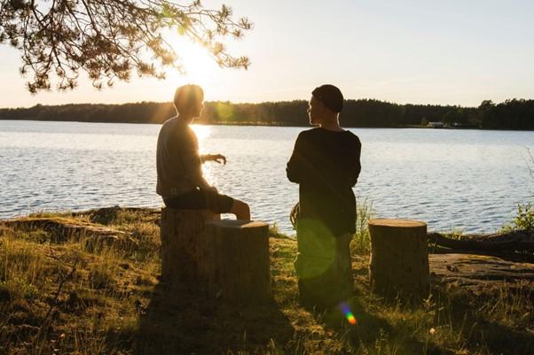 Two people sitting by a lake talking