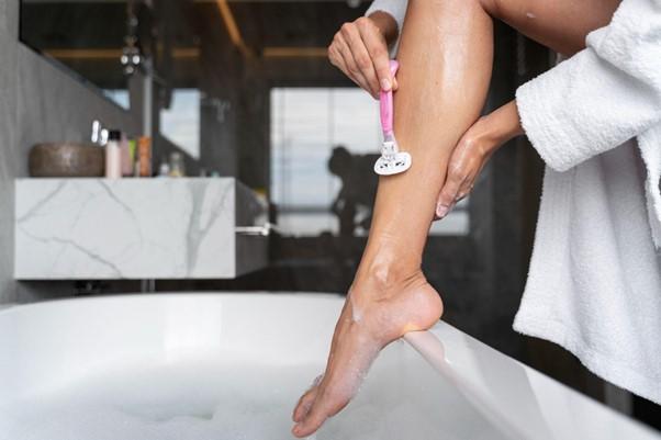 Woman shaving leg over bath
