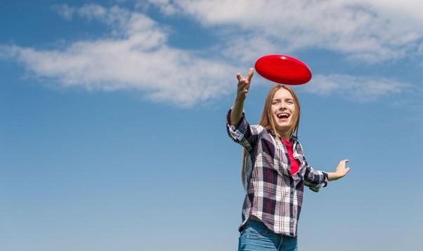 Young woman throwing a red frisbee