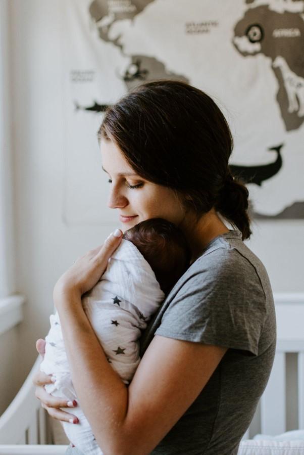 Mother holding her baby next to a crib