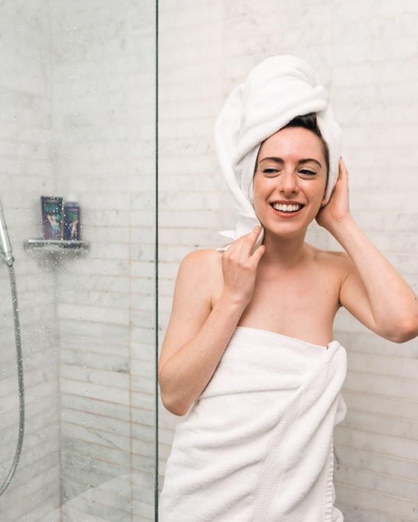 A woman getting out of the shower wearing a towel